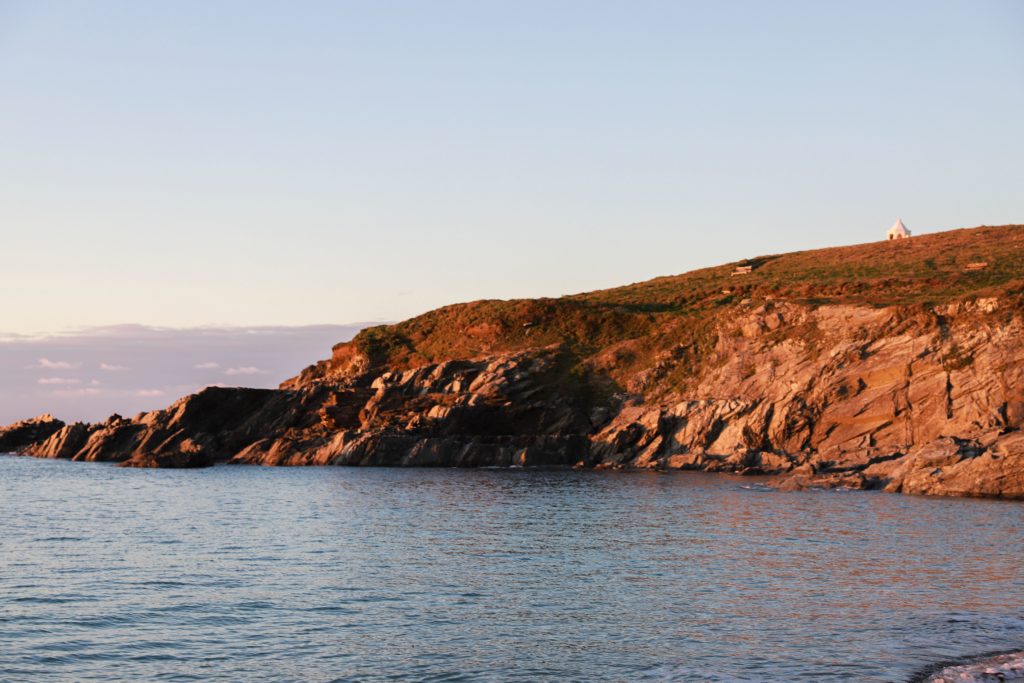 little fistral beach at sunset with the light reflecting off the rocks